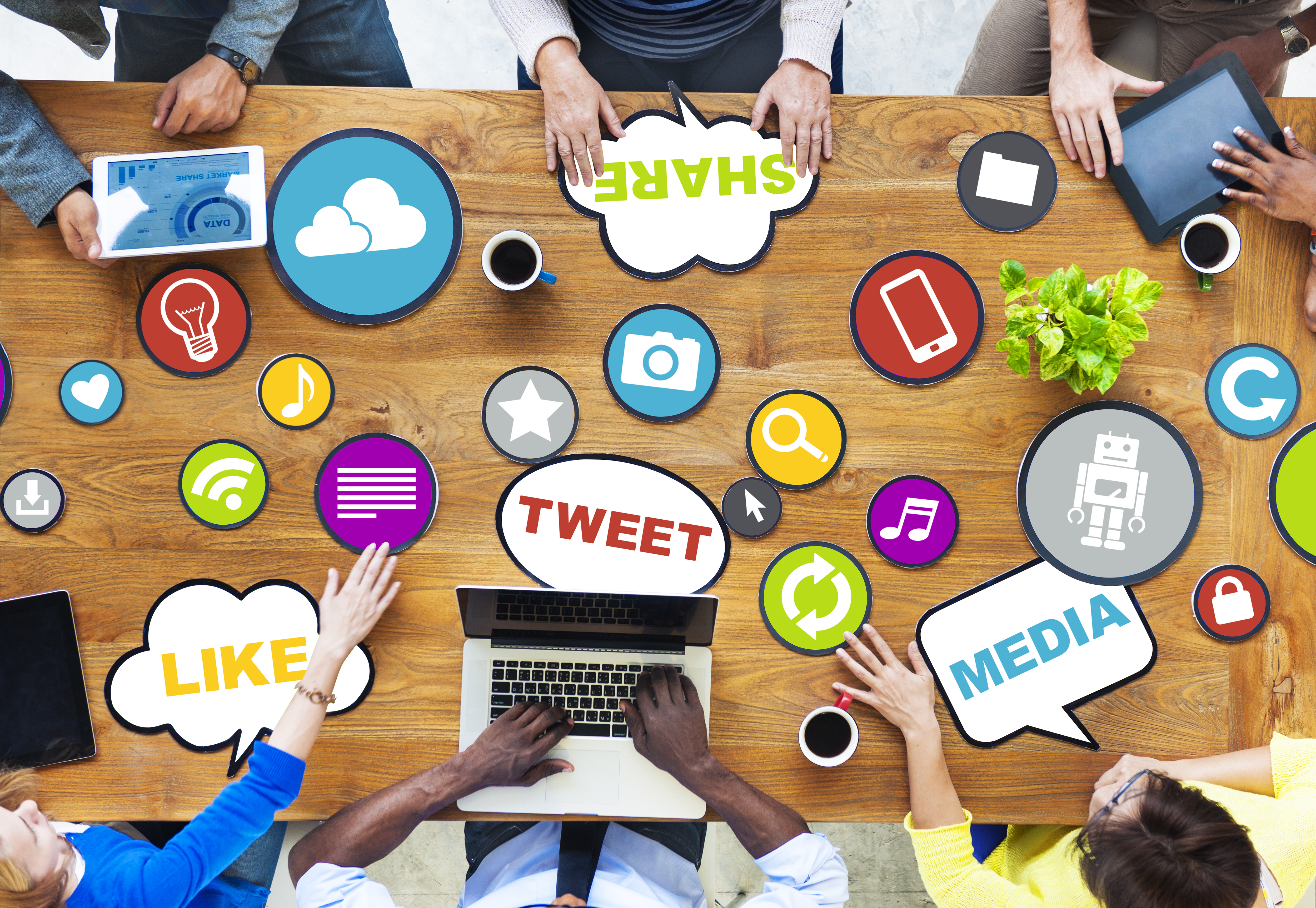 People sitting around a table, sharing ideas on digital devices